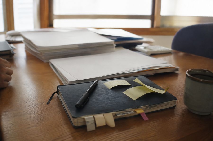 事務所の机に置かれた書類とノートと湯呑み